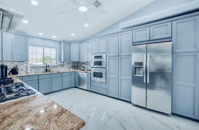 kitchen featuring appliances with stainless steel finishes, tasteful backsplash, vaulted ceiling, and light stone counters