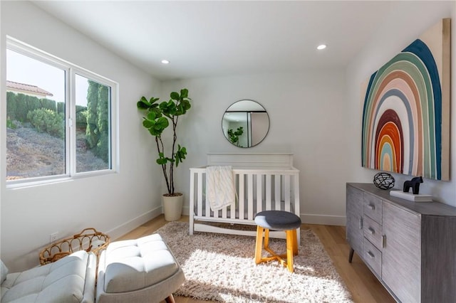 bedroom featuring light wood-type flooring and a nursery area