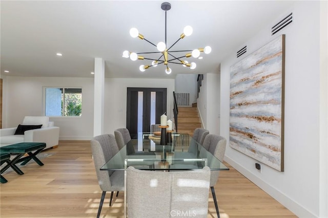 dining room with light hardwood / wood-style floors and an inviting chandelier