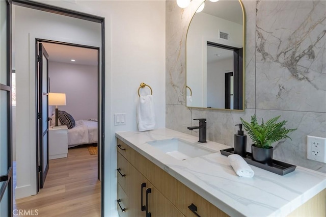 bathroom with vanity, wood-type flooring, and tasteful backsplash