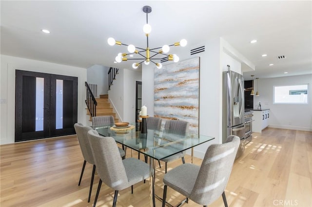 dining space with light hardwood / wood-style floors and a chandelier