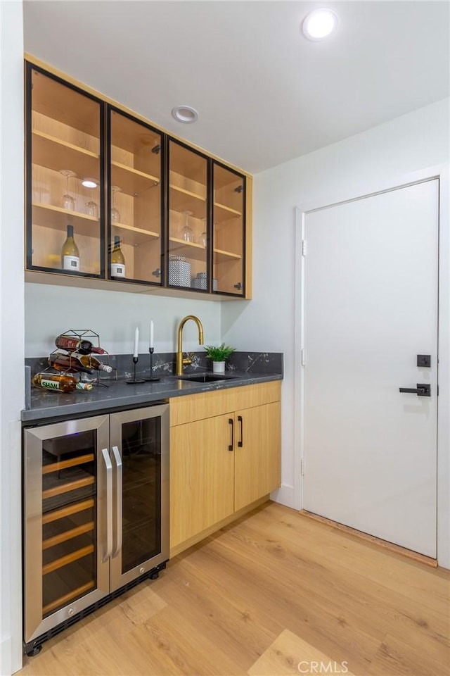 bar featuring wine cooler, light brown cabinetry, light hardwood / wood-style floors, and sink