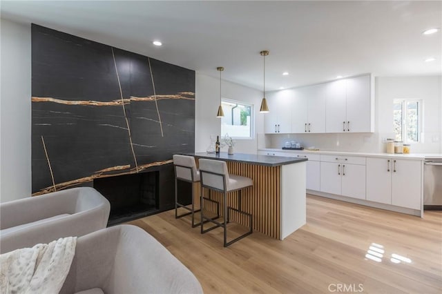 kitchen featuring a kitchen breakfast bar, light hardwood / wood-style flooring, white cabinetry, and hanging light fixtures