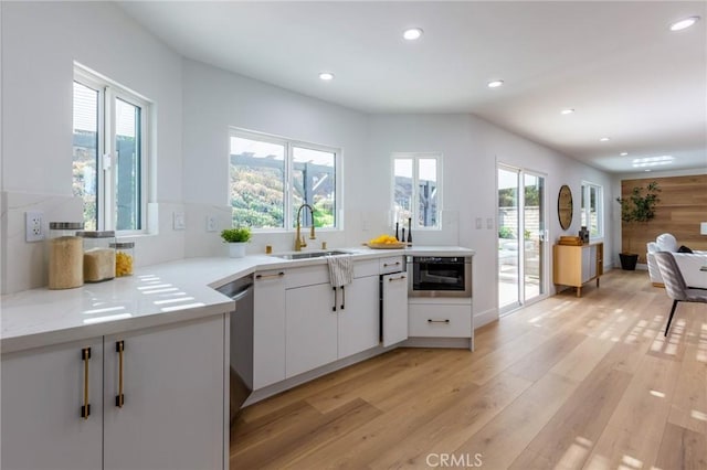 kitchen with white cabinetry, light hardwood / wood-style flooring, a healthy amount of sunlight, and sink