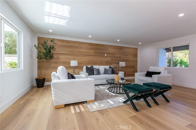 living room featuring wood walls, a wealth of natural light, and light hardwood / wood-style flooring