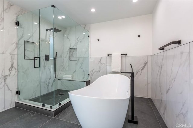 bathroom featuring tile patterned flooring, tile walls, and plus walk in shower