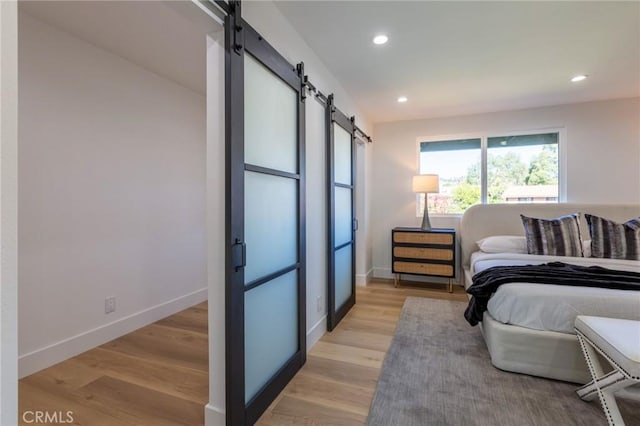 bedroom featuring a barn door and light hardwood / wood-style floors