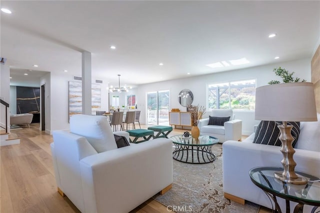 living room featuring a chandelier, a wealth of natural light, and light hardwood / wood-style flooring