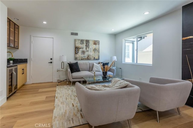 living room with light wood-type flooring, sink, and wine cooler