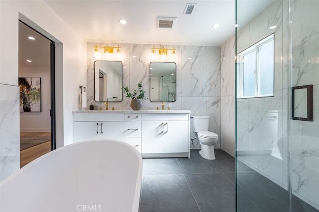 bathroom with vanity, tile walls, tile patterned flooring, toilet, and a tub