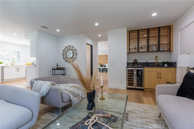 living room featuring light hardwood / wood-style floors, wet bar, and wine cooler