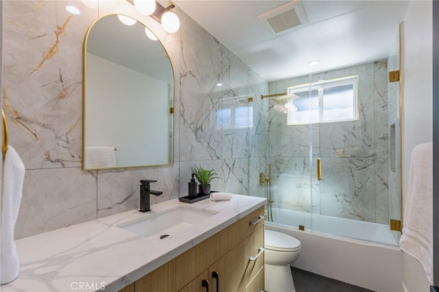 full bathroom featuring vanity, backsplash, combined bath / shower with glass door, toilet, and tile walls