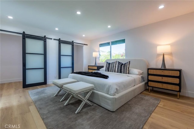 bedroom featuring wood-type flooring and a barn door