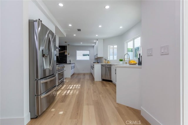 kitchen with white cabinetry, sink, light hardwood / wood-style floors, and appliances with stainless steel finishes