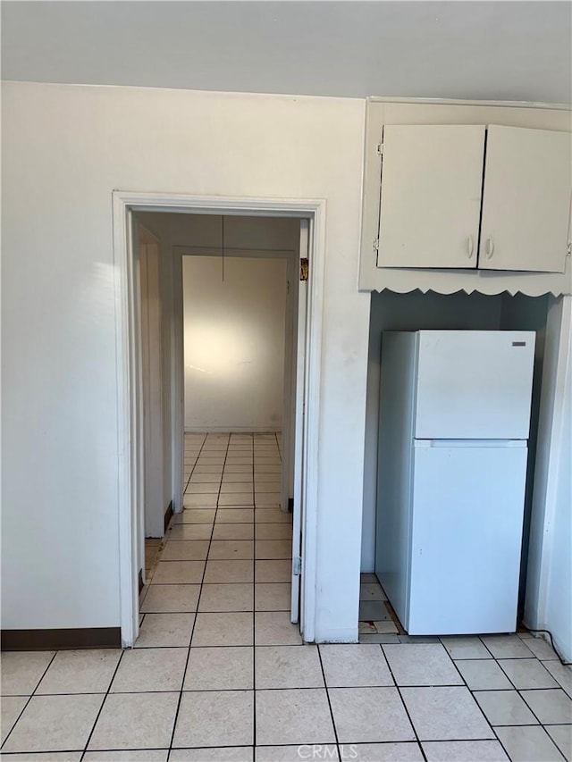 kitchen with white cabinets, white fridge, and light tile patterned floors