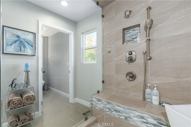 bathroom with toilet, tile patterned flooring, and tiled shower
