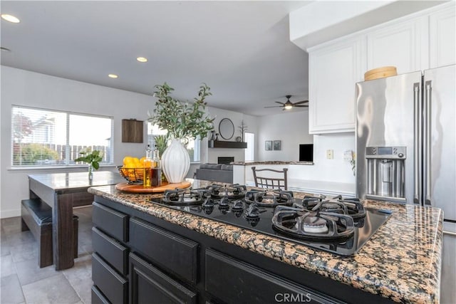 kitchen featuring ceiling fan, white cabinets, black gas stovetop, and dark stone countertops