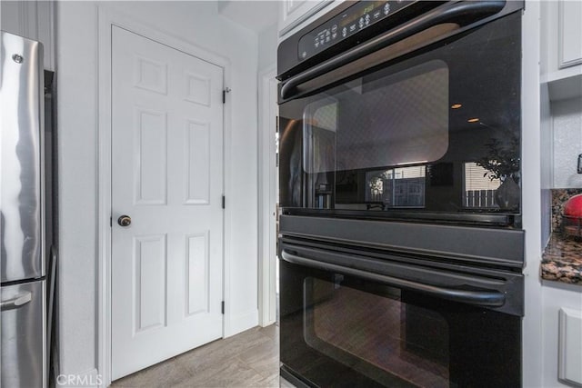 details with white cabinetry, double oven, and stainless steel refrigerator