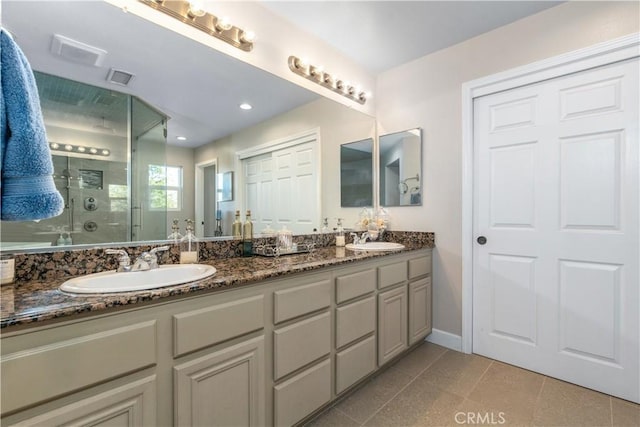 bathroom featuring a shower with shower door, vanity, and tile patterned flooring