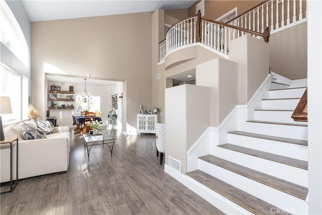 stairway with a high ceiling, wood-type flooring, and a chandelier