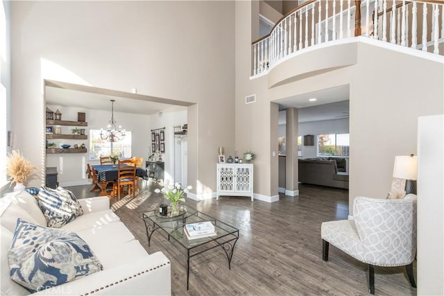 living room with a towering ceiling, hardwood / wood-style floors, and a notable chandelier