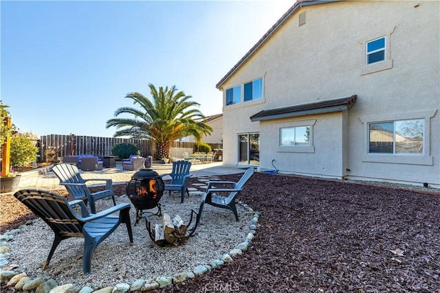 rear view of property with an outdoor living space with a fire pit and a patio