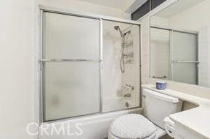 full bathroom featuring vanity, toilet, and bath / shower combo with glass door