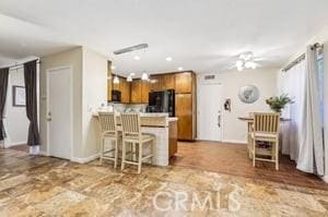 kitchen featuring kitchen peninsula, ceiling fan, a breakfast bar, and black fridge