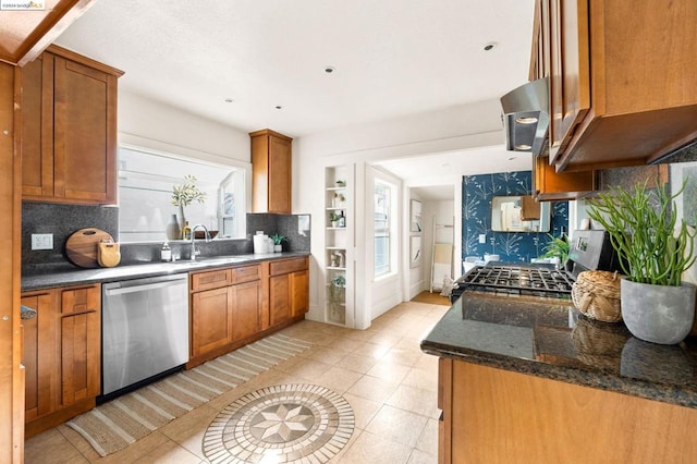 kitchen featuring ventilation hood, sink, decorative backsplash, dark stone countertops, and stainless steel appliances