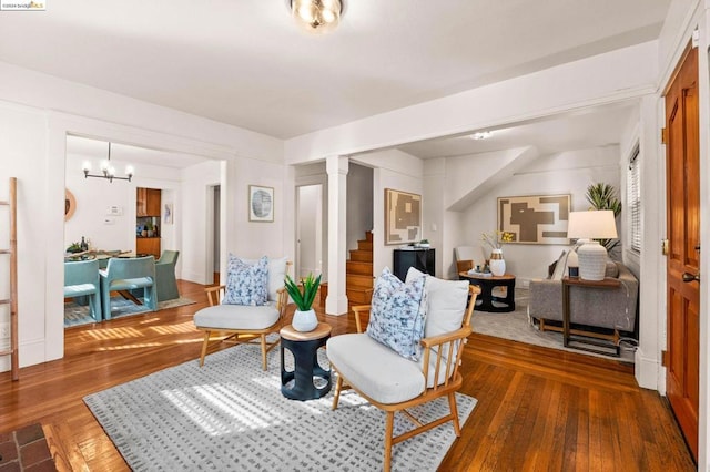 sitting room featuring a chandelier, hardwood / wood-style floors, and decorative columns