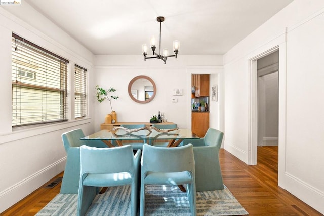 dining room with dark hardwood / wood-style floors and an inviting chandelier