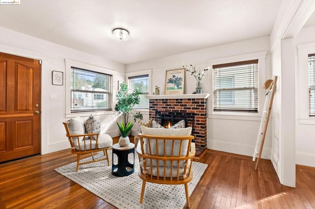 sitting room featuring wood-type flooring and a brick fireplace