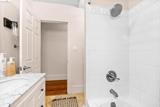 bathroom with hardwood / wood-style floors, vanity, and tiled shower / bath