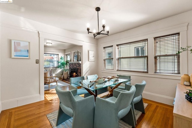 dining room featuring hardwood / wood-style floors, a fireplace, and an inviting chandelier