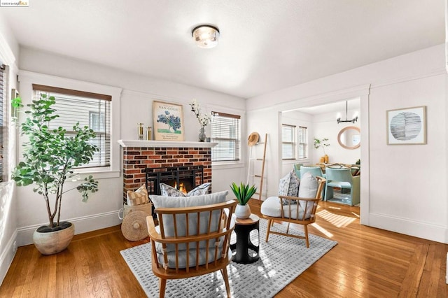 living area featuring a brick fireplace and hardwood / wood-style flooring