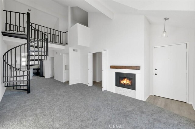 unfurnished living room featuring high vaulted ceiling and dark carpet