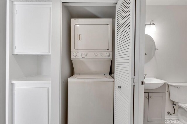 laundry area with stacked washing maching and dryer and sink