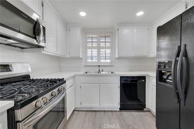 kitchen featuring light wood-type flooring, white cabinets, sink, and black appliances