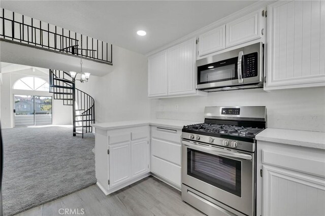 kitchen with white cabinetry, hanging light fixtures, a notable chandelier, stainless steel appliances, and light carpet