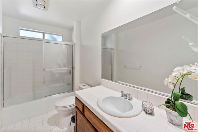 full bathroom featuring shower / bath combination with glass door, vanity, toilet, and tile patterned flooring