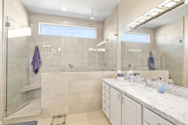 bathroom featuring tile patterned flooring, vanity, a shower with shower door, and tile walls