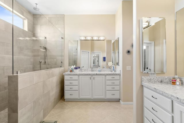 bathroom with a tile shower, vanity, and tile patterned floors