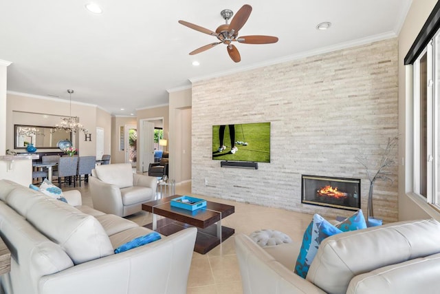 tiled living room with a stone fireplace, a healthy amount of sunlight, ceiling fan with notable chandelier, and ornamental molding