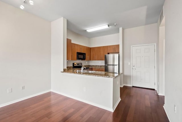 kitchen featuring sink, appliances with stainless steel finishes, dark hardwood / wood-style floors, kitchen peninsula, and stone counters