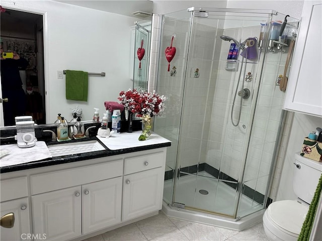 bathroom featuring tile patterned floors, vanity, toilet, and a shower with door