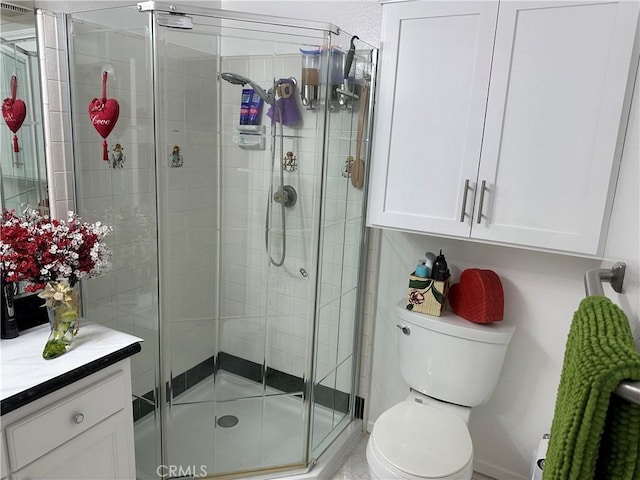 bathroom featuring vanity, a shower with shower door, and toilet