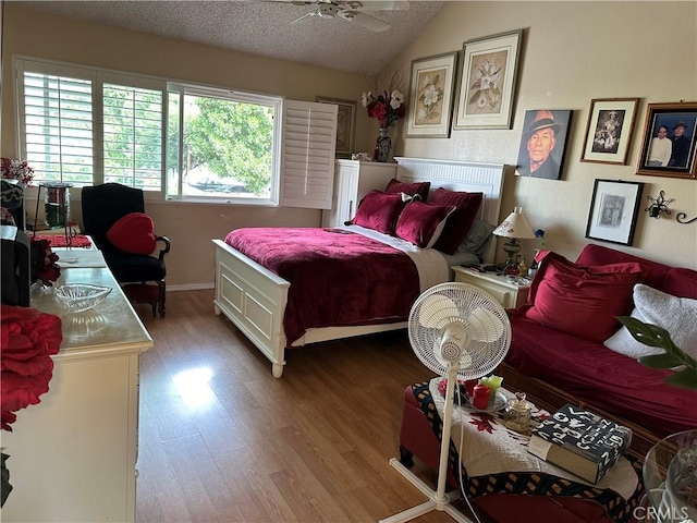 bedroom with hardwood / wood-style floors, ceiling fan, lofted ceiling, and a textured ceiling