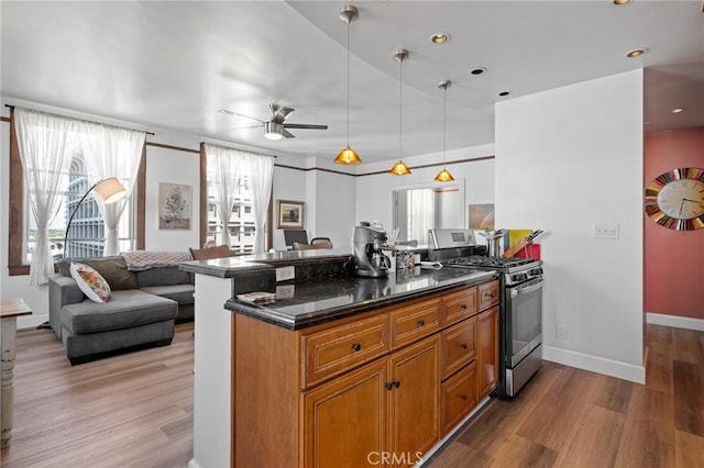 kitchen with gas stove, kitchen peninsula, pendant lighting, and light wood-type flooring