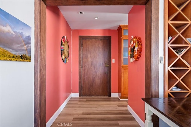 hallway with light hardwood / wood-style floors and beam ceiling