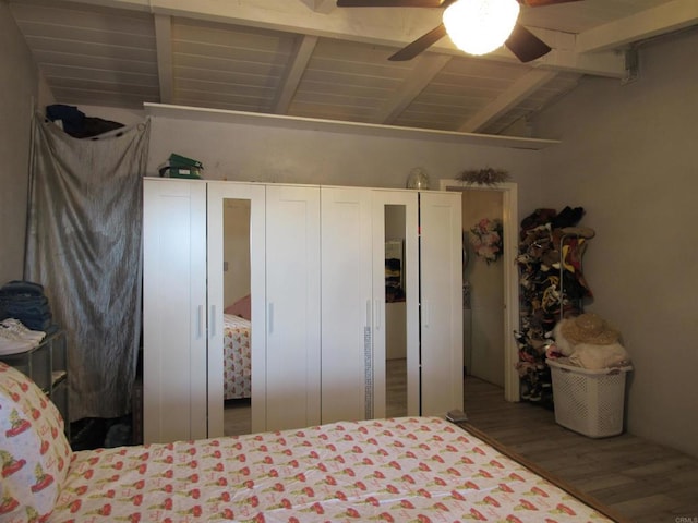 bedroom featuring wood-type flooring, vaulted ceiling with beams, and ceiling fan